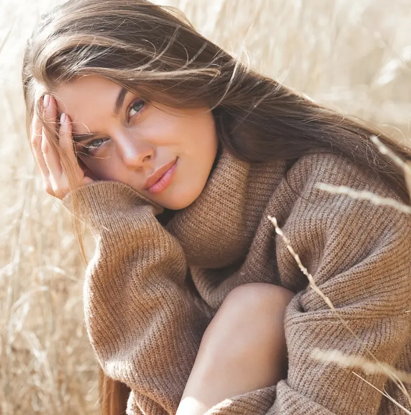 Woman in brown sweater sitting in a field